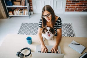 Woman on laptop, with dog on lap