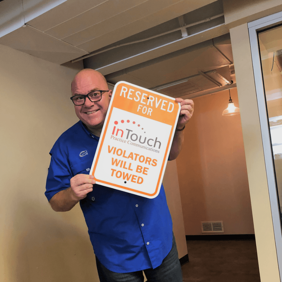 smiling man holding InTouch parking sign