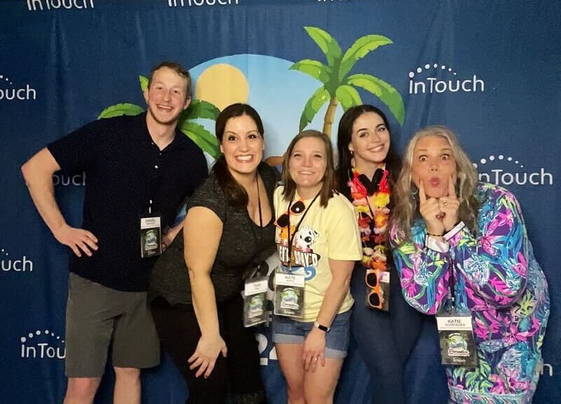 group of 5 people posing in front of intouch beach banner