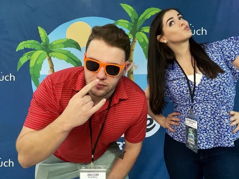 man and woman posing in front of intouch beach banner